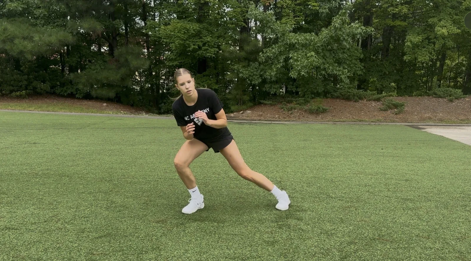 A volleyball athlete in a wide athletic stance mid change of direction