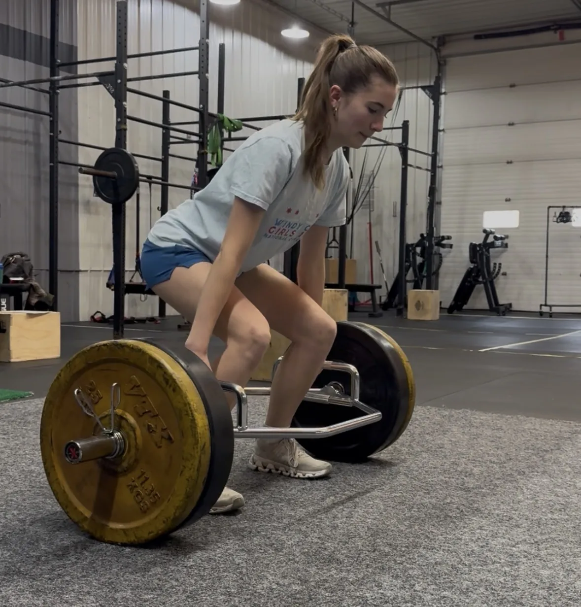 A volleyball athlete setting her back before lifting a loaded barbell from the floor